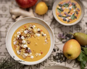 Dekorierte vegane Kürbissuppe mit vegetarischem Topping im Vordergrund und Veganem Topping im Hintergrund